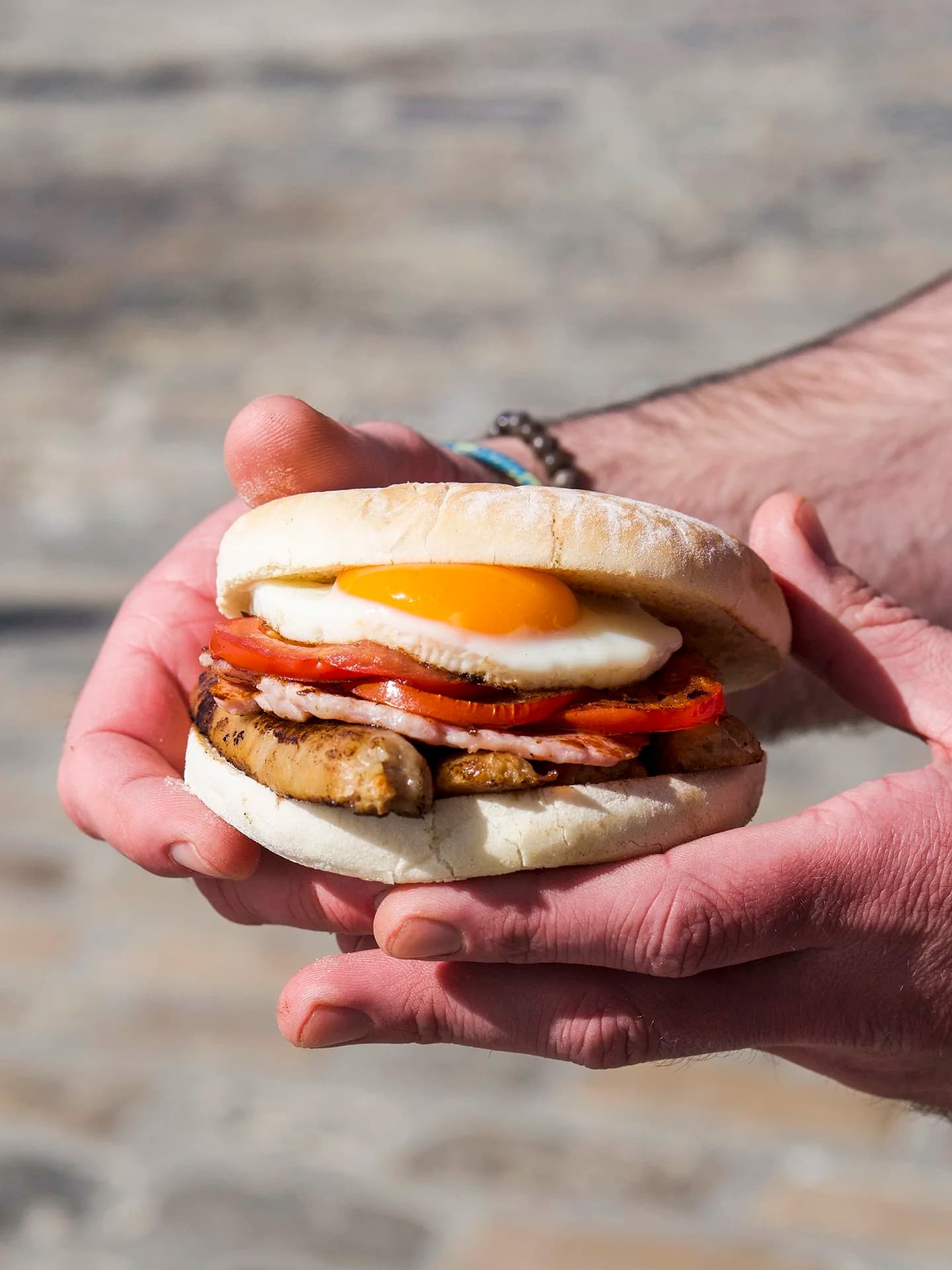 A filled breakfast bap held in hand at the counter.