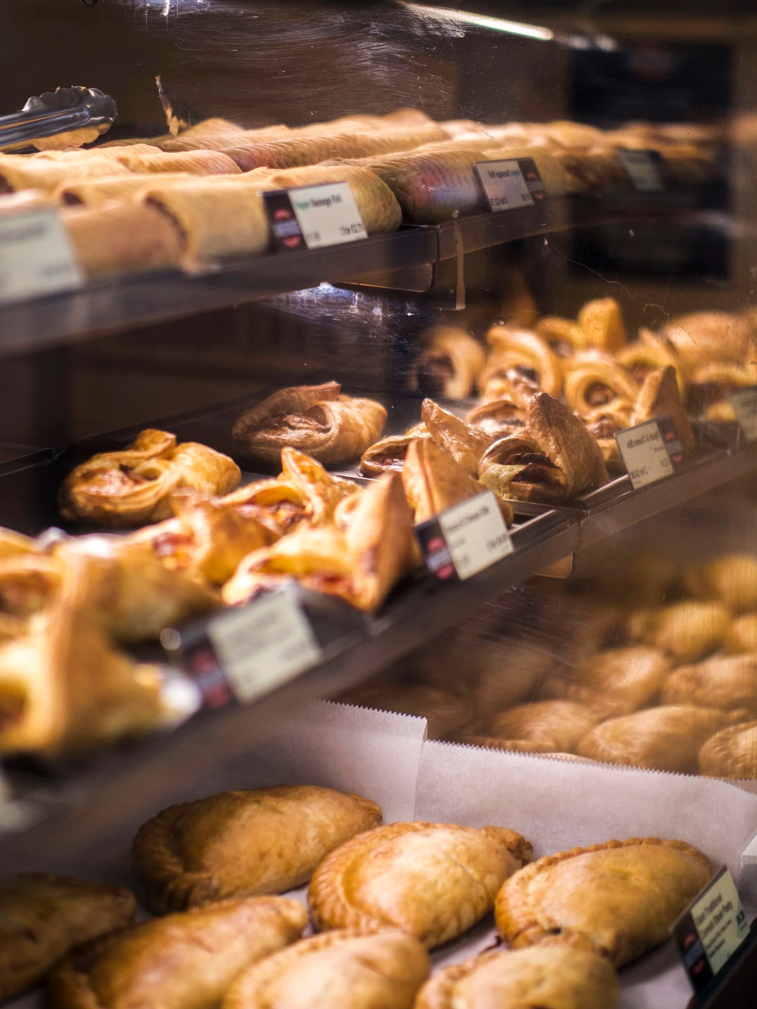 A lit bakery glass counter with chrome price-ticket tabs.