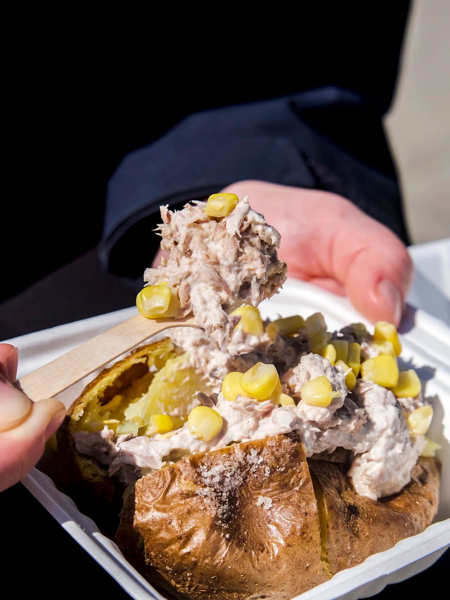 A loaded jacket potato held in hand.